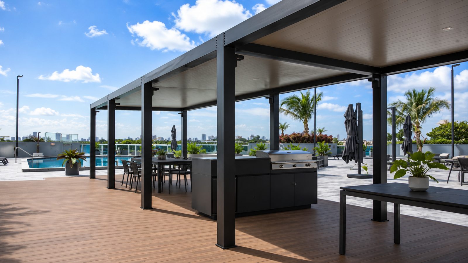 Black aluminum covers over an outdoor kitchen and dining area on a rooftop pool deck