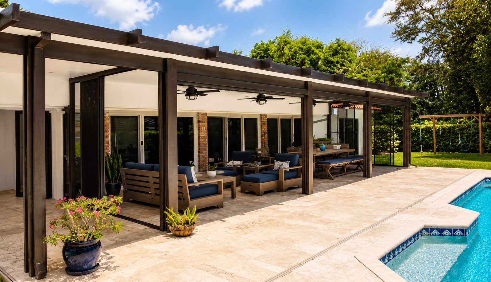Bronze aluminum patio cover with decorative rafter tails over a poolside living and dining area, screens open