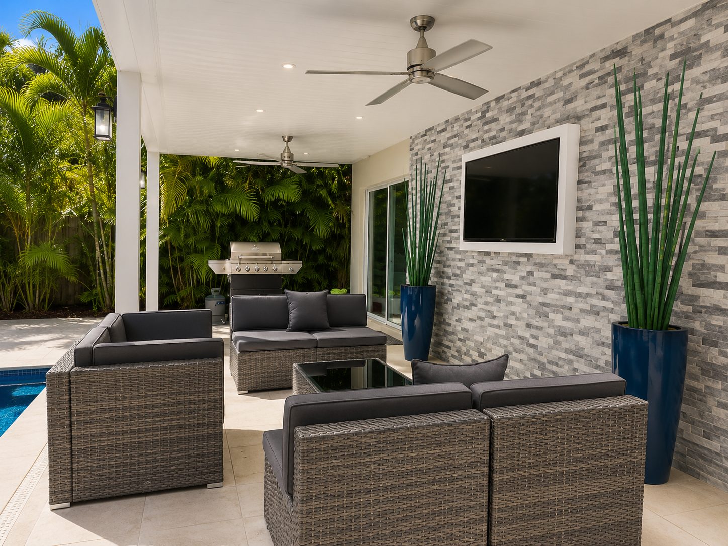 View beneath a white aluminum patio cover with ceiling fans and recessed lighting over a poolside seating area
