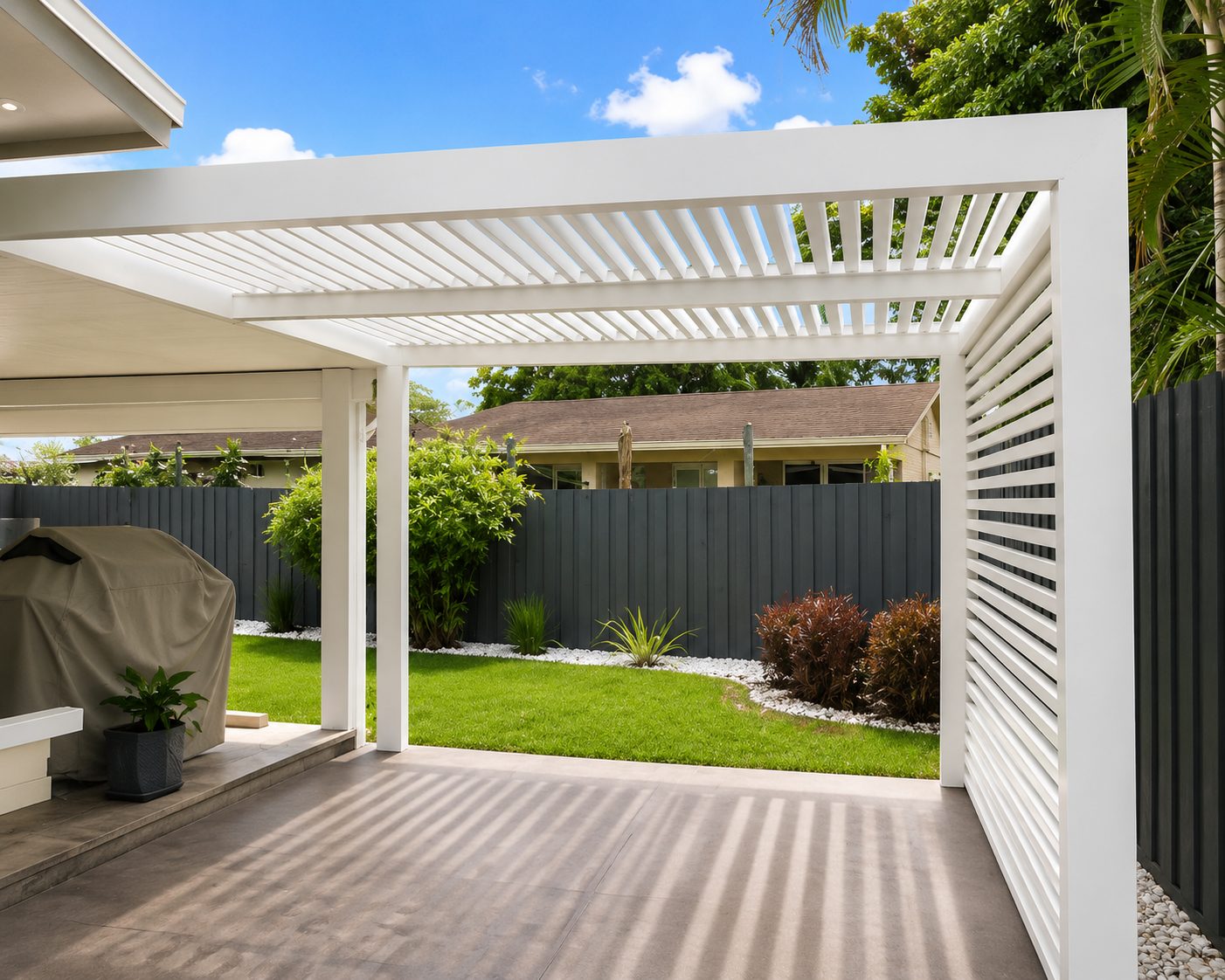 White aluminum louvered pergola with a slatted privacy wall over a backyard grill area